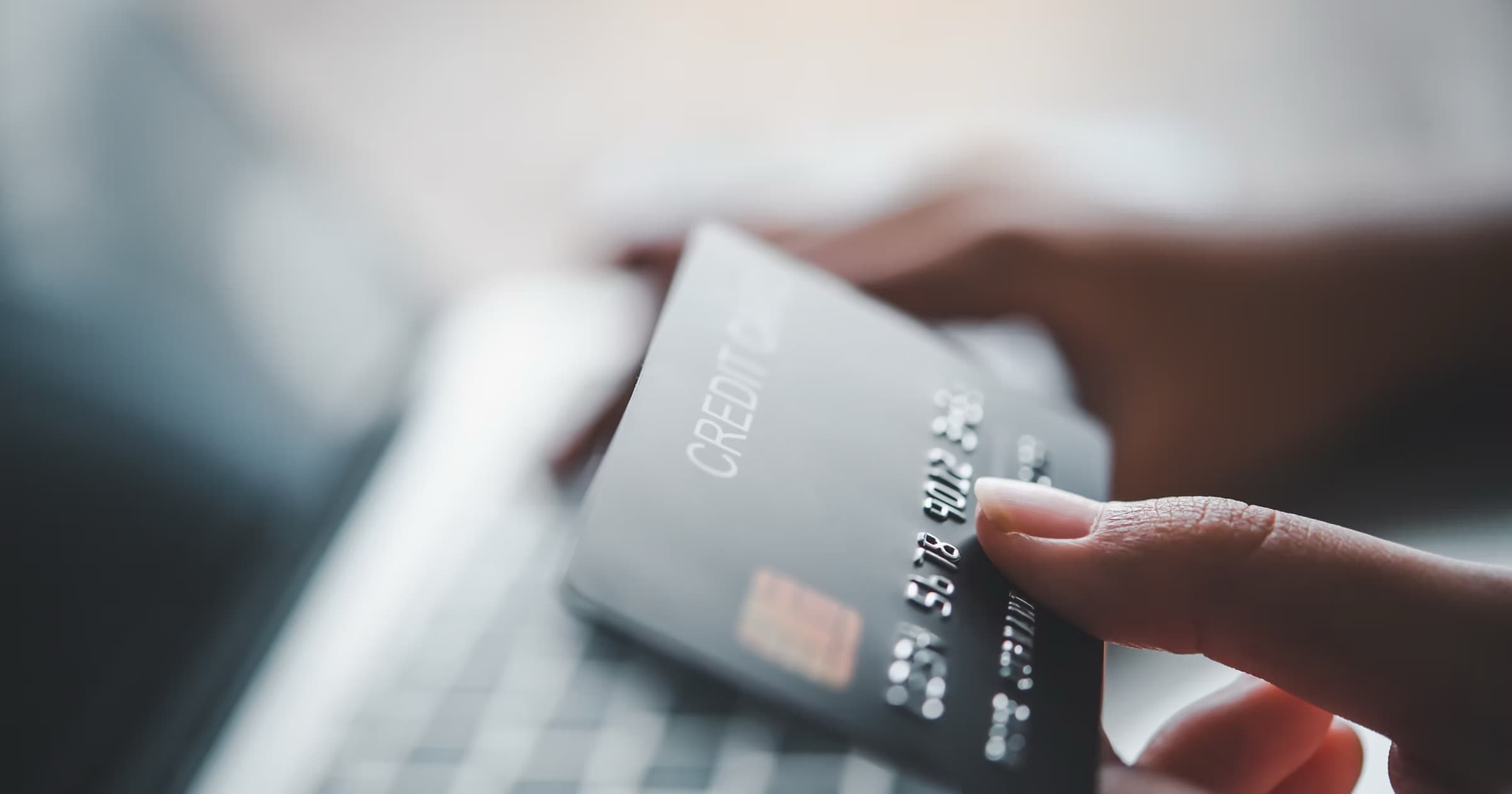 Customer holding a credit card next to a laptop